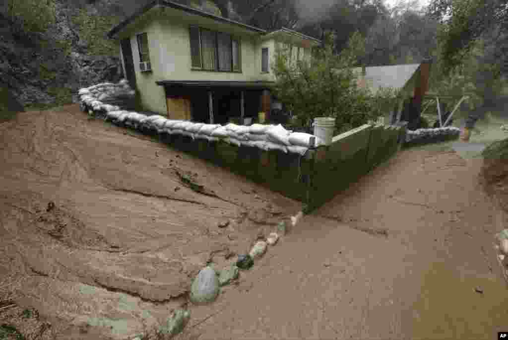 A mud flow skirts a house protected with sandbags in Monrovia, California, Jan. 6, 2016. A wildfire two years ago stripped away vegetation and loosened soil.