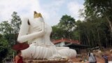 A Buddhist monk and villagers examine a damaged Buddha statue following an earthquake in Chiang Rai province, northern Thailand.