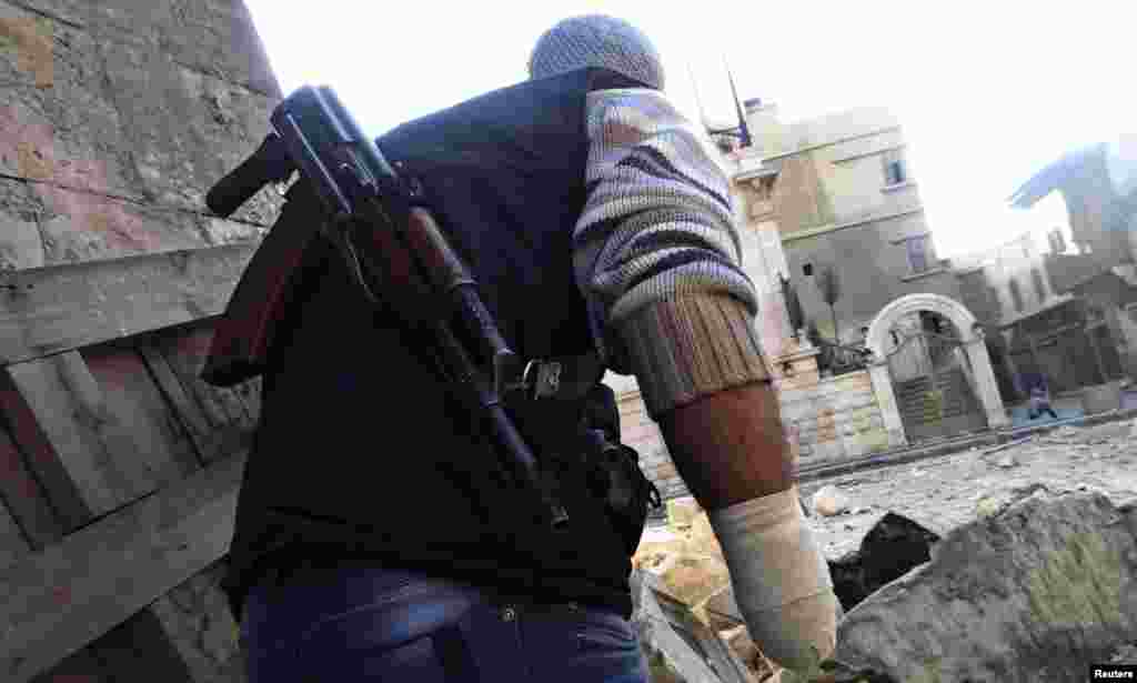 A Free Syrian Army fighter with an amputated hand, takes cover from a sniper loyal to Syria&#39;s President Bashar al -Assad, near Aleppo&#39;s historic citadel, November 28, 2012.
