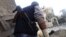 A Free Syrian Army fighter with an amputated hand, takes cover from a sniper loyal to Syria's President Bashar al -Assad, near Aleppo's historical citadel, November 28, 2012.