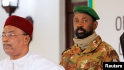 FILE - Colonel Assimi Goita, leader of Mali's military junta, stands behind Niger's President Mahamadou Issoufou during a photo opportunity after the Economic Community of West African States consultative meeting in Accra, Ghana, Sept. 15, 2020.