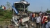People stand near the wreckage of a bus that collided with a truck in Barabanki district, Uttar Pradesh state, India, Oct.7, 2021.