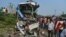 People stand near the wreckage of a bus that collided with a truck in Barabanki district, Uttar Pradesh state, India, Oct.7, 2021.