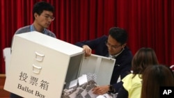 FILE - Election workers empty a ballot box to count votes for a district council election at a polling station in Hong Kong, Nov. 24, 2019. 