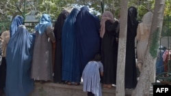 Las mujeres afganas desplazadas internamente, que huyeron de la provincia del norte debido a la batalla entre talibanes y fuerzas de seguridad afganas, se reúnen para recibir alimentos gratuitos ded manos de hombres chiítas en Kabul el 13 de agosto de 2021.