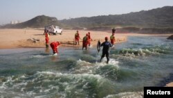 Members of a hazardous waste cleanup crew collect dead fish after chemicals entered the water system from a warehouse which was burned during days of looting following the imprisonment of former South African President Jacob Zuma, in Durban, July 17, 2021