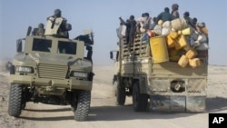 East African civilians depart in a truck, right, as AMISOM forces advance on al-Shabab-controlled region, Somalia, Sept. 4, 2012.