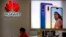 A sales clerk looks at his smartphone in a Huawei store at a shopping mall in Beijing Wednesday, July 4, 2018. 