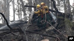 Firefighters Valarie Lopez, left, and Mark Tabaez work to cool hot spots after a wildfire burned a hillside in Clayton, Georgia, Nov. 15, 2016. The fire zone has spread from northern Georgia and eastern Tennessee into eastern Kentucky and the western Carolinas.