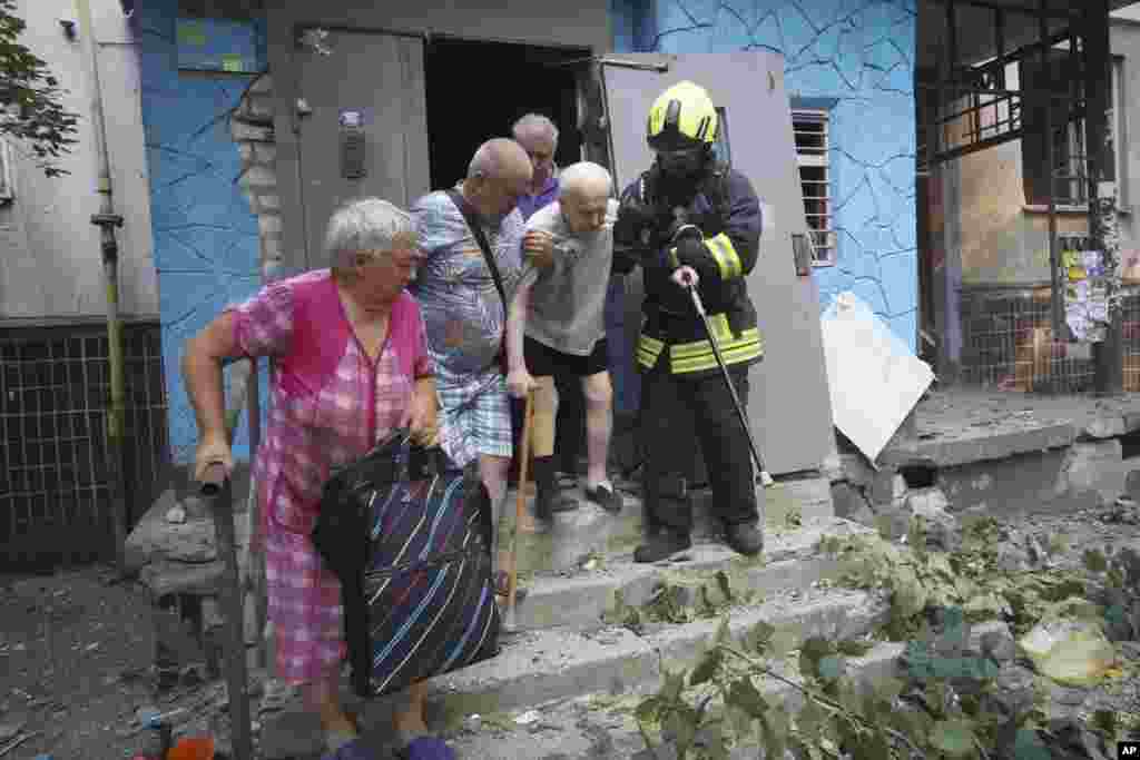 Rescatistas ayudan a ancianos a salir de su casa dañada después de un ataque aéreo de Rusia en Járkov, Ucrania, el 30 de agosto de 2024. (Foto AP/Andrii Marienko)