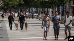 La gente camina por el Paseo del Prado mientras miembros de la policía patrullan en La Habana, Cuba, el lunes 11 de julio de 2022, un año después de que las protestas más grandes en décadas sacudieran al gobierno unipartidista de Cuba. (Foto AP/Ramon Espinosa).