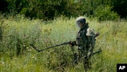 Un experto ruso en remoción de minas trabaja para encontrar y desactivar minas a lo largo de la línea de alto voltaje en Mariúpol, en el este de Ucrania, el 13 de julio de 2022.