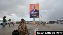 Un résident passe devant l'affiche de campagne du président sortant de la Côte d'Ivoire, Alassane Ouattara, dans une rue d'Abidjan le 15 octobre 2020.