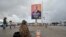 Un résident passe devant l'affiche de campagne du président sortant de la Côte d'Ivoire, Alassane Ouattara, dans une rue d'Abidjan le 15 octobre 2020.