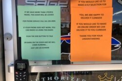 In this photo taken March 20, 2020, a sign outside a fly fishing shop in Maupin, Oregon, advises customers of new policies to limit the spread of the coronavirus in rural areas.