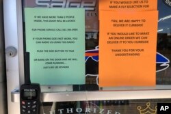 In this photo taken March 20, 2020, a sign outside a fly fishing shop in Maupin, Oregon, advises customers of new policies to limit the spread of the coronavirus in rural areas.