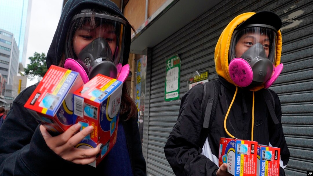 Warga mengenakan masker penutup wajah sambil membawa paket berisi masker sekali pakai di Hong Kong, 5 Februari 2020. 