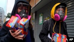 Warga mengenakan masker penutup wajah sambil membawa paket berisi masker sekali pakai di Hong Kong, 5 Februari 2020. 