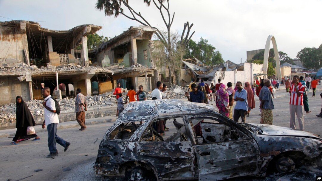 Warga Somalia berjalan melewati bangunan dan mobil yang hancur akibat serangan bom bunuh diri di Mogadishu, Somalia (27/2).