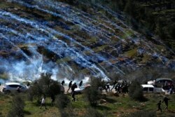 FILE - Palestinian demonstrators run away from tear gas fired by Israeli forces during a protest against Israeli settlements and U.S. President Donald Trump's Mideast initiative, in the West Bank village of Beita near Nablus, Feb. 28, 2020.