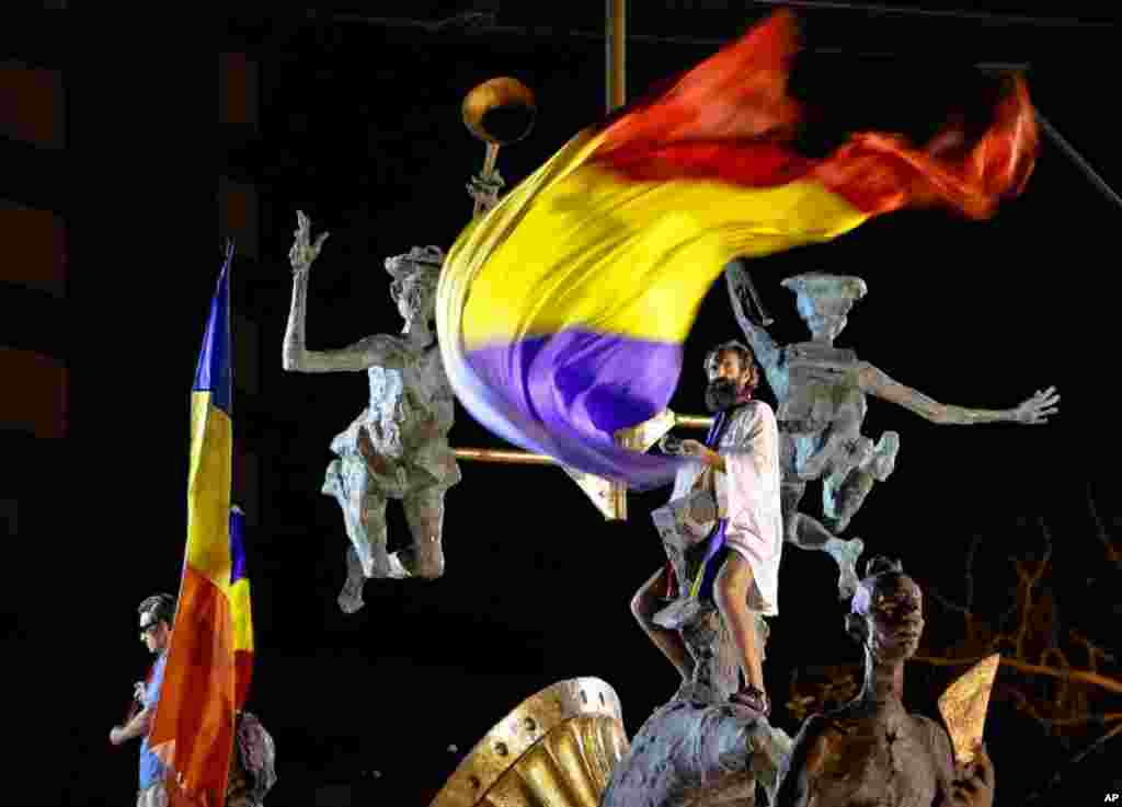 مردی پرچم رومانی را طی اعتراضات عليه ترايان باسسکو، رييس جمهوری در دست دارد.(AP)