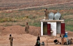 Fighters from the Syrian Democratic Forces, SDF, stand guard at the Syrian side of the border with Iraq near Rabiaa border crossing, Iraq, Oct. 16, 2019.