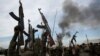 FILE - Rebel fighters hold up their rifles as they walk in front of a bushfire in a rebel-controlled territory in Upper Nile State, South Sudan February 13, 2014.