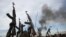 FILE - Rebel fighters hold up their rifles as they walk in front of a bushfire in a rebel-controlled territory in Upper Nile State, South Sudan February 13, 2014.