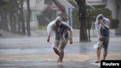 People struggle against strong wind and rain caused by approaching Typhoon Vongfong as they wallk on a street in Naha on Japan's southern island of Okinawa, in this photo taken by Kyodo, Oct. 11, 2014. 