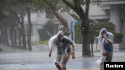 Warga di jalanan kota Naha di Okinawa, Jepang, di tengah badai Vongfong (11/10).