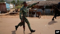 Un policier centrafricain pourchasse des pillards qui attaquent un camion en panne au PK 12, le dernier point de contrôle à la sortie de Bangui, 7 février 2014. (AP Photo / Jerome Delay)