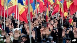 FILE - People raise their hands during an anti-government protest in Chisinau, Moldova, Jan. 24, 2016. The election of a pro-Russian president in the impoverished former Sovet republic is widely seen as a vote against the pro-Europe policies of previous Moldovan leaders.