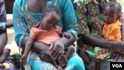 Fourteen-month-old Georgette Lukaji (L) rests in her mother's lap as she and other children wait to be treated at a roadside UNICEF clinic, in Kananga, Democratic Republic of Congo. (A. Powell/VOA)