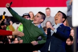 FILE - Democratic presidential candidate Andrew Yang, right, takes a photograph with a member of the audience as he arrives at New Hampshire Technical Institute's Concord Community College, Feb. 8, 2020, in Concord, N.H.