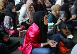 In this Dec. 27, 2019, photo, Amani Al-Khatahtbeh, center, sits near the back of the room at the Islamic Center of New York University during Friday prayers.