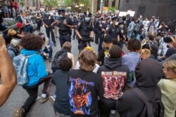 New York City police officers confront protesters in the street as they take a knee to demonstrate against the the death of George Floyd.