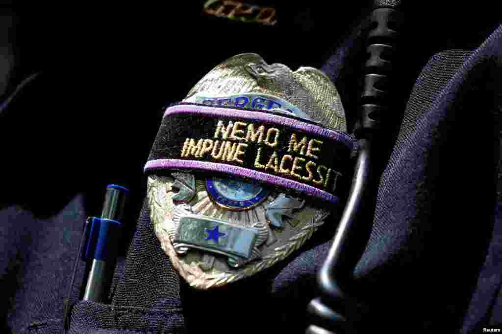 A Dallas police officer wears a mourning band on his badge that loosely translates to "No one can harm me unpunished" during a prayer vigil in a park following the multiple police shooting in Dallas, Texas, July 8, 2016.