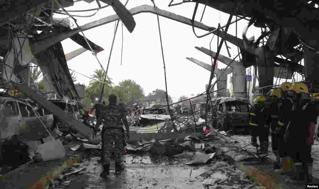 Iraqi security forces and firefighters inspect the site of a suicide attack in Hilla, Iraq, March 9, 2014.&nbsp;