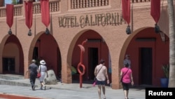 FILE - Tourists walk along the streets of the town of Todos Santos, Baja California Sur, Mexico, May 2, 2017. 