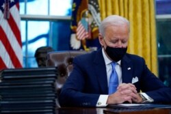 FILE - President Joe Biden pauses as he signs his first executive orders in the Oval Office of the White House, Jan. 20, 2021.