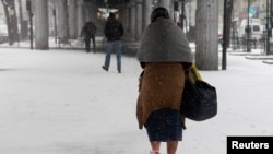 A homeless woman, her feet wrapped in plastic, walks in the snow in Paris, March 12, 2013 as winter weather with snow and freezing temperatures returns to northern France. 