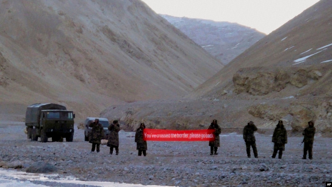 FILE - In this May 5, 2013, file photo, Chinese troops hold a banner which reads "You've crossed the border, please go back" in Ladakh, India. India says it is ready to hold talks with China with both sides pulling back their forces to end a standoff along a disputed territory high in the Himalayan mountains.