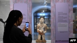 FILE - A gallery assistant takes a picture of a statue during a press preview ahead of the opening of the exhibition ReThinking Collections at the AfricaMuseum in Tervuren, northwest of Brussels, on January 17, 2024.