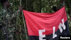 FILE - Rebels of the National Liberation Army (ELN) hold a banner in the northwestern jungles in Colombia, Aug. 30, 2017. 