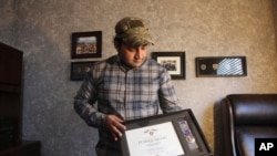 In this Monday, Dec. 16, 2019, photo, Zia Ghafoori displays the Purple Heart at his home in Charlotte, N.C., that he received while working with U.S. Forces in Afghanistan.