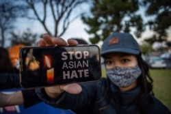 Julie Tran holds her phone during a candlelight vigil in Garden Grove, California, on March 17, 2021 to unite against the recent spate of violence targeting Asians and to express grief and outrage after an Atlanta shooting left eight people dead.