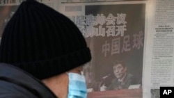 FILE - A man looks at a kiosk displaying a newspaper with a photo of Chen Xuyuan, head of the Chinese Football Association, in Beijing, Feb. 15, 2023. 