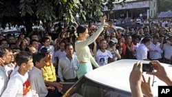 NLD ရုံးချုပ်ရှေ့တွင် ထောက်ခံသူများကို နှုတ်ဆက်နေသည့် ဒေါ်အောင်ဆန်းစုကြည်။ နိုဝင်ဘာ ၁၅၊ ၂၀၁၀။