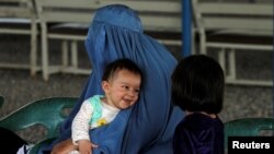 An Afghan refugee woman waits with her children to be repatriated to Afghanistan, at the United Nations High Commissioner for Refugees office on the outskirts of Peshawar, Pakistan April 3, 2017. 