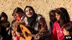 FILE - Ruaa Hassouna plays music for Palestinian children on her oriental lute in an activity aimed to support the children's mental health, amid continuing battles between Israel and the militant group Hamas, in Rafah in in the southern Gaza Strip on December 18, 2023.